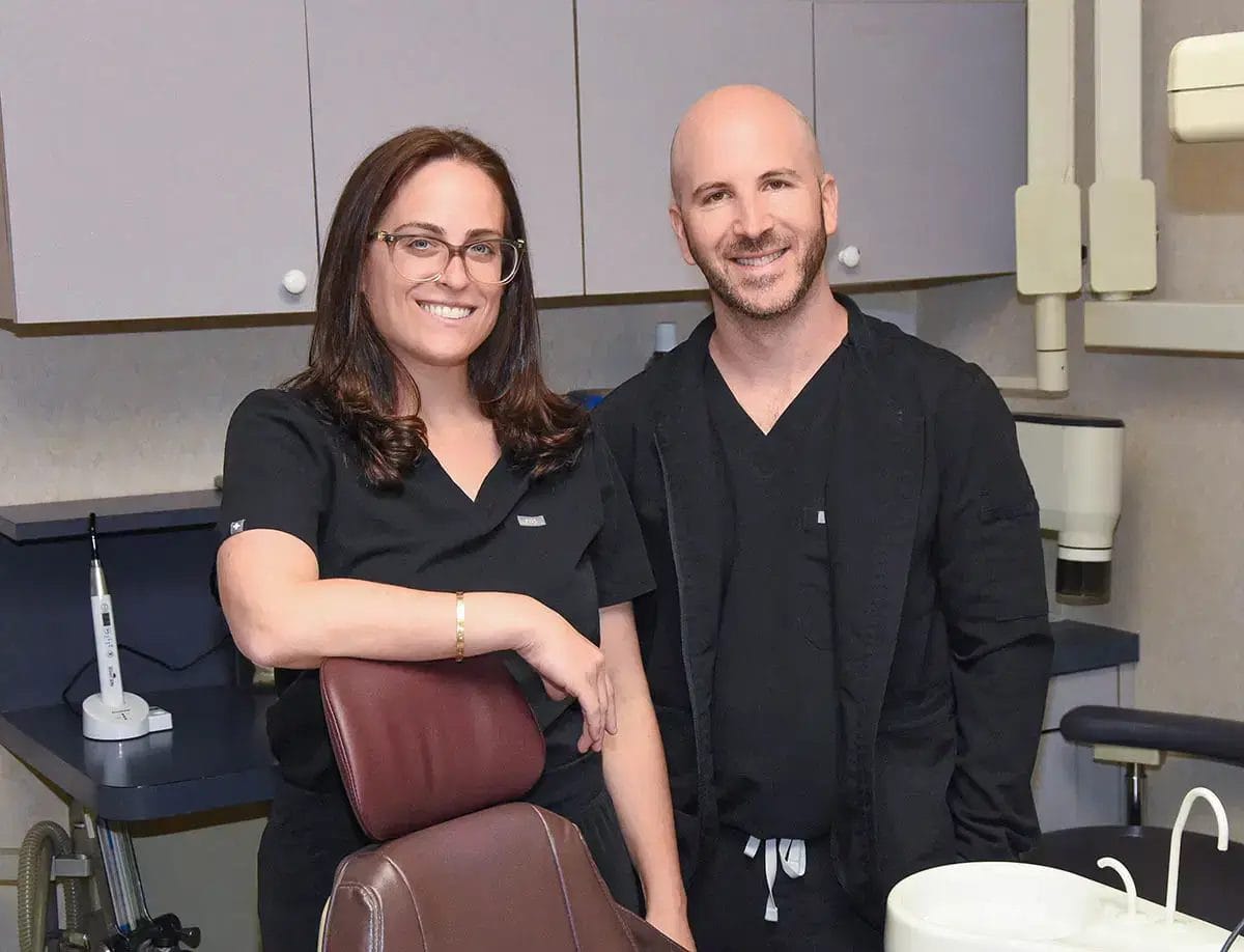Dr. Kevin Henner and a dental professional smiling in their modern restorative dentistry office in Valley Stream.
